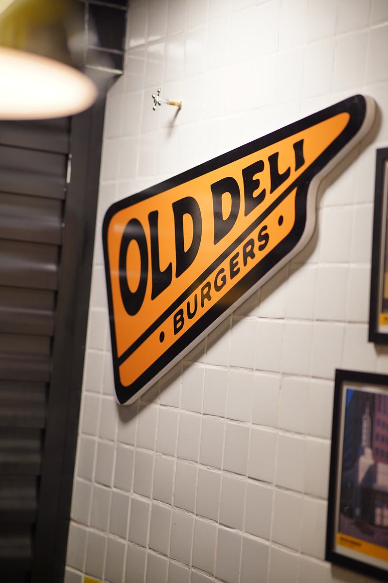 Flâmula Old Deli Burgers na parede de azulejos